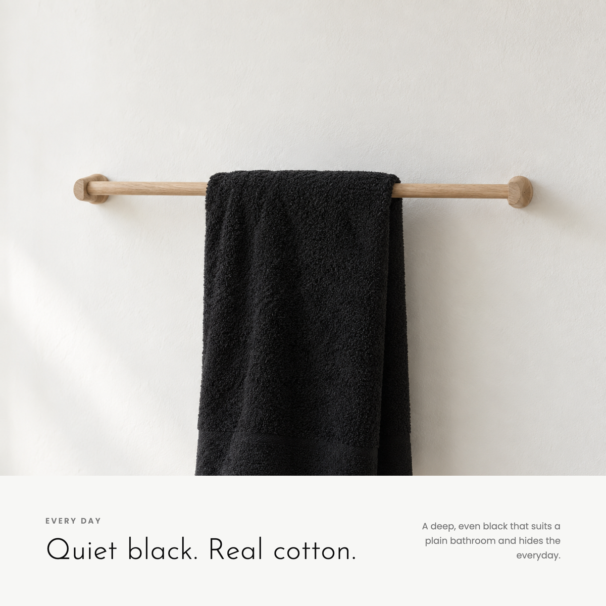 Carbon Towel hanging on an oak rail in a plain white bathroom